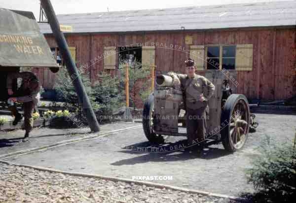 American GI soldier standing beside captured German 15 cm sIG 33 Howitzer. Army barracks. Homburg Germany 1945