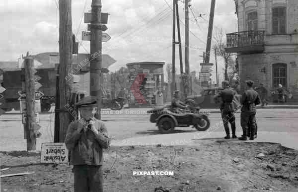 BW Russian boy music play sign posts motorbike with sidecar trucks russian town summer 1942