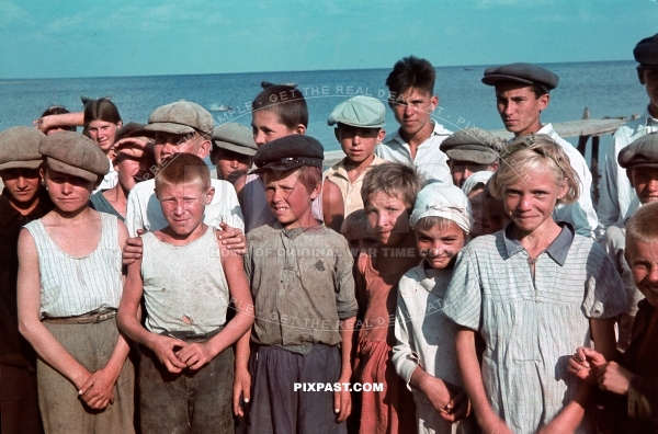German officer photographing a group of young Ukrainian children standing in front of the Sea of Asov Ukraine 1941