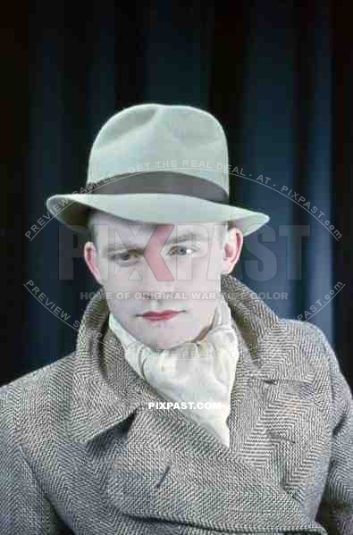 Young Austrian man in American style 20s hat and jacket with red lipstick, theatre show 1937, Later becomes war reporter.