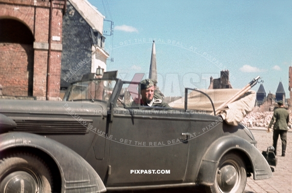 Army driver in his 1938 Opel Super 6 Cabriolet staff car in destroyed french town France 1940. 297 Infantry Division