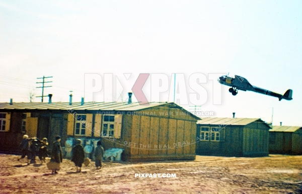 German Luftwaffe Dornier-17 bomber plane flaying over the roof of a workers camp. Children with suitcases. Germany 1941