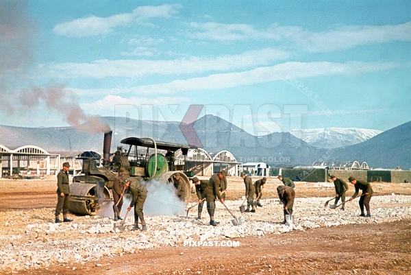 German RAD soldiers rebuilding an old destroyed airport air strip in Yugoslavia 1943. With a large steam tractor roller