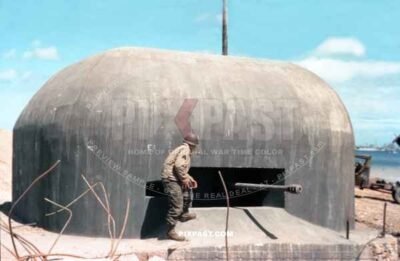 American Cameraman with pipe and 16mm film camera inspects a captured Artillery Bunker. Normandy D-Day plus 10