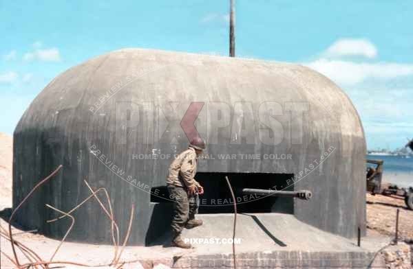 American Cameraman with pipe and 16mm film camera inspects a captured Artillery Bunker. Normandy D-Day plus 10