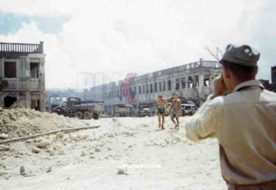 American GMC Jimmy cargo trucks parked outside a blown up Japanese government building. Naha Okinawa 1945