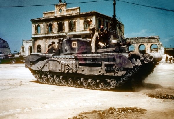 British army Churchill Tank Number 7 driving passed heavily bombed Italian train station. Italy July 1944
