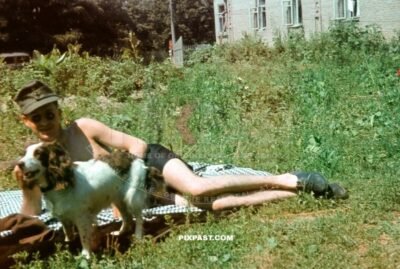 German Gebirgsjager soldier in summer shorts with pet dog Wolfe beside Russian school house. Russia 1942