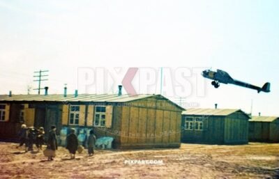 German Luftwaffe Dornier-17 bomber plane flaying over the roof of a workers camp. Children with suitcases. Germany 1941