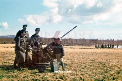 German Luftwaffe Flak Unit stationed in Oslo Norway 1940. Little boy wearing army helmet beside FLAK gun. 20-mm Flak