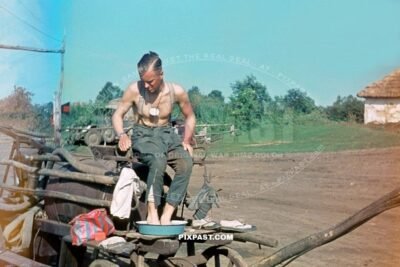 German army soldier wearing dog tags washing his feet with red soap on a water horse wagon. Russia summer 1941 September