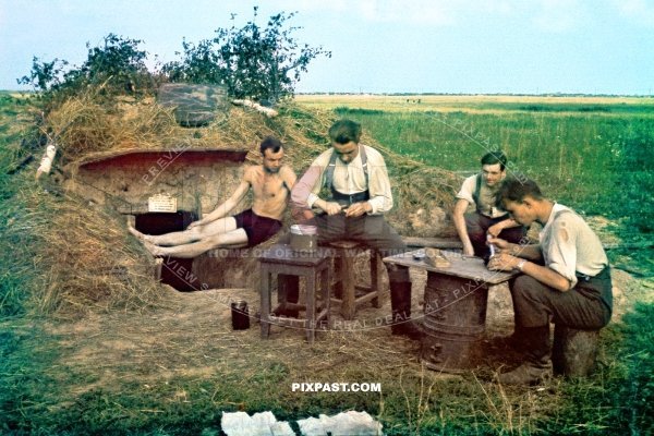 German army soldiers eating lunch in their canteens beside a earth bunker in Estonia 1943