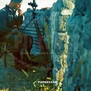 German soldier eating an apple in front of his camouflaged army telescope binoculars. Old ruins wall. France 1940