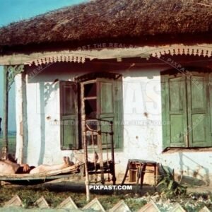 German soldier sleeping on bed outside small cottage. Ukrainian village. Ukraine 1942
