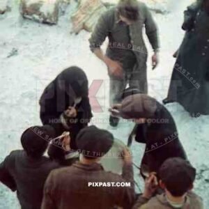 Jewish Forced labour eating on a Starvation Diet in Polish Ghetto. Winter 1942. German police guard watches.
