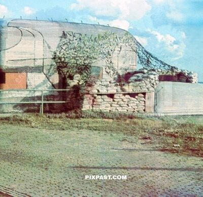 Massive military artillery bunker on the French coast. Colorful camouflage and sand bags and netting. France 1940