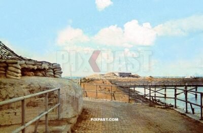 Massive military artillery bunker on the French coast. Colorful camouflage and sand bags and netting. France 1940