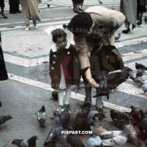Mother feeding birds with daughter in Odeonsplatz in Munich, Germany 1938, behind Feldherrnhalle,