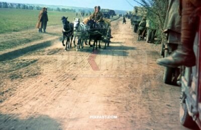 Romanian army retreating from Russian front line. Horse wagon and camouflage trucks flood dirt road. Russia 1944