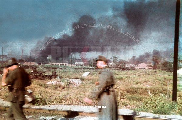 Two German Wehrmacht soldiers walking on a rail track beside a burning factory on the outskirts of Stalingrad Russia 1942