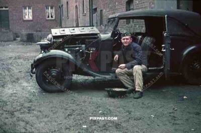 Wehrmacht soldier repairing car in Niederaußem, Germany 1940