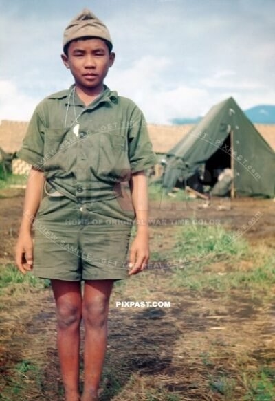 Young New Guinea boy in make shift American tropical army uniform helping US troops in New Guinea 1944