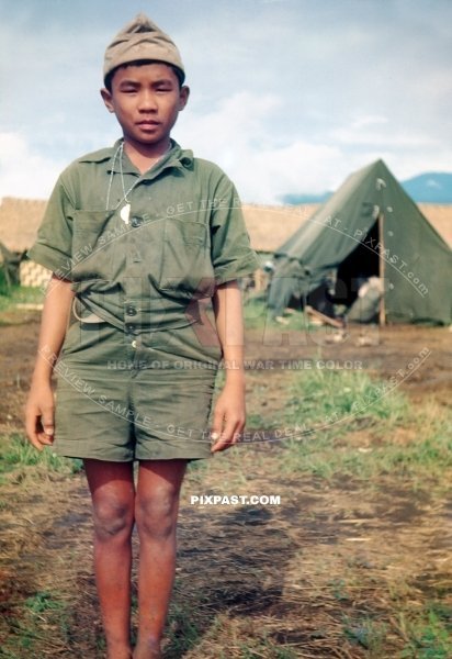 Young New Guinea boy in make shift American tropical army uniform helping US troops in New Guinea 1944