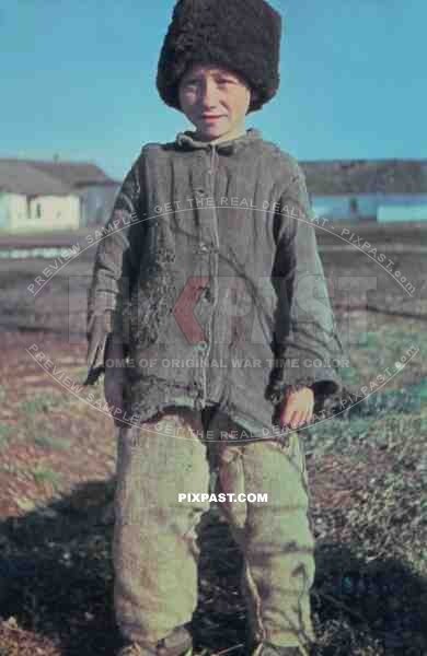 Young Russian farmer boy wearing traditional hat in Village. photographed by German war reporter. Russia 1943.
